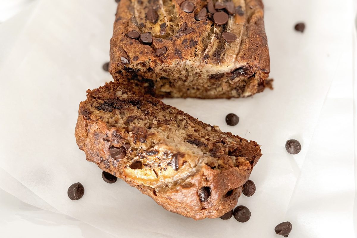 One slice of Chocolate Chips Walnuts Banana Bread and the rest of the bread displayed on white plate.