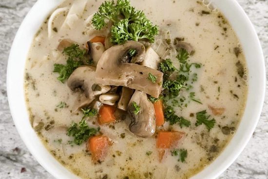 Mushroom soup with carrots, noodles and fresh parsley in a soup bowl